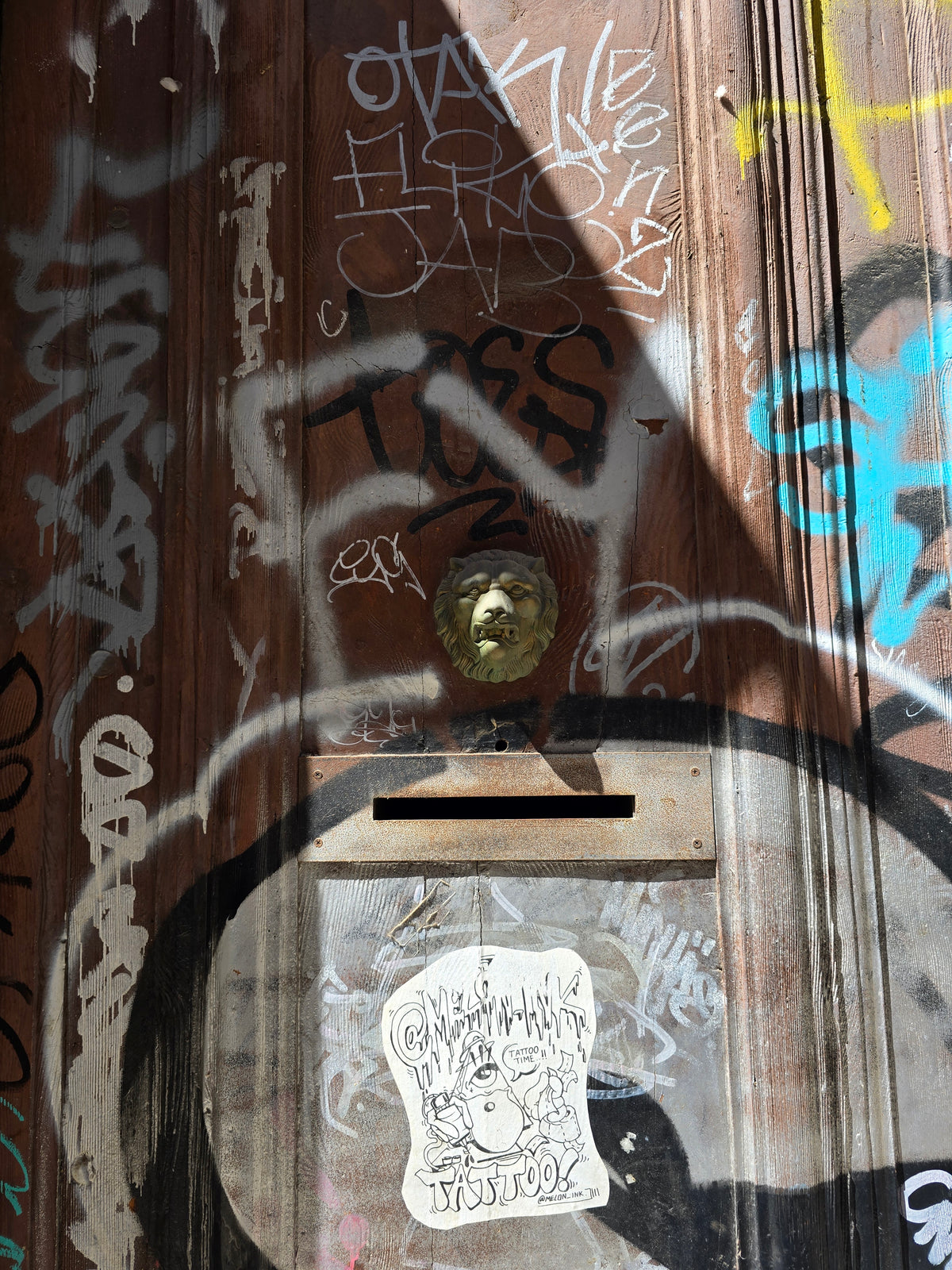 Weathered wooden mailbox covered in colorful graffiti and stickers on a Barcelona street.